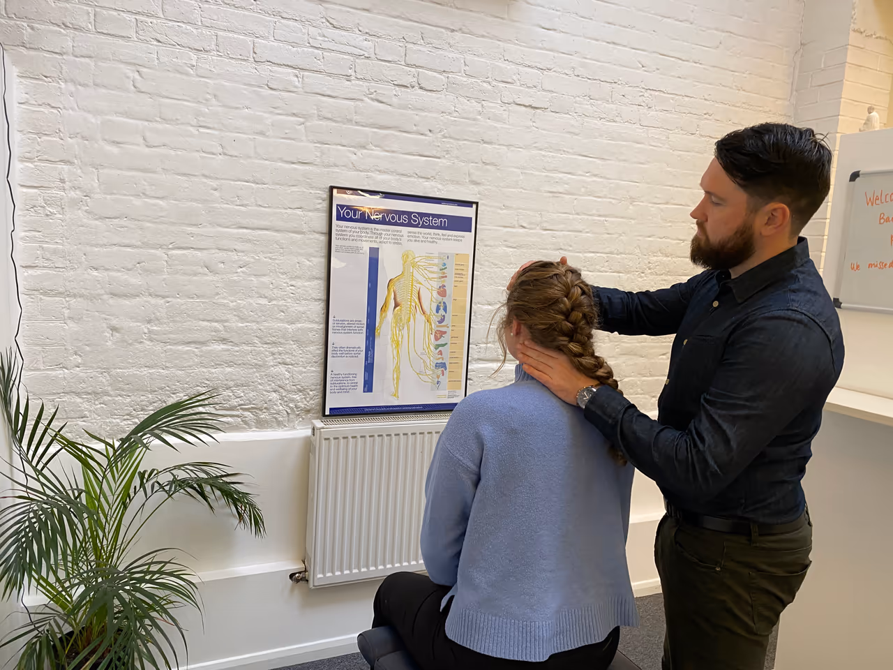 Chiropractor assessing a standing patient’s neck and shoulders