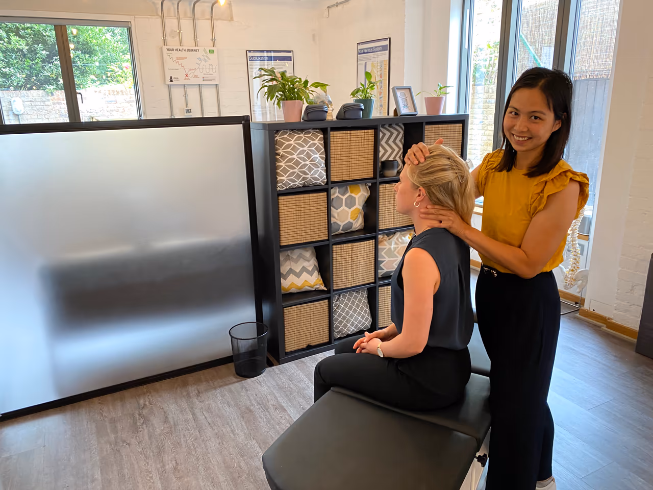 Chiropractor checking a seated patient’s posture from behind