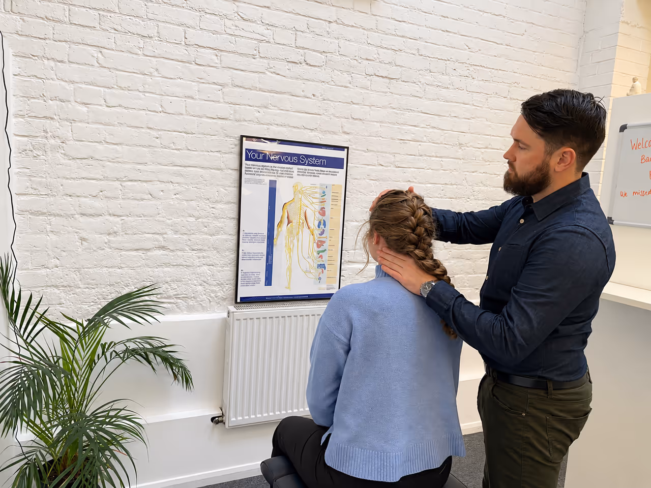 Chiropractor assessing a standing patient’s neck and shoulders