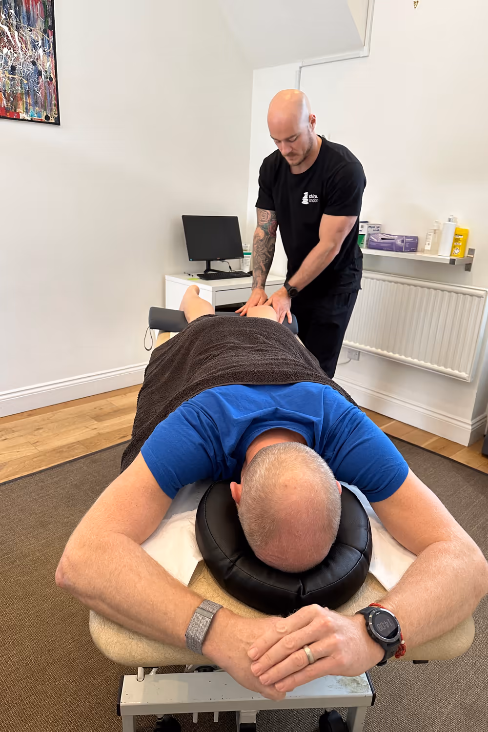 Sports therapist performing a back and shoulder massage on a patient at a Chiro London clinic